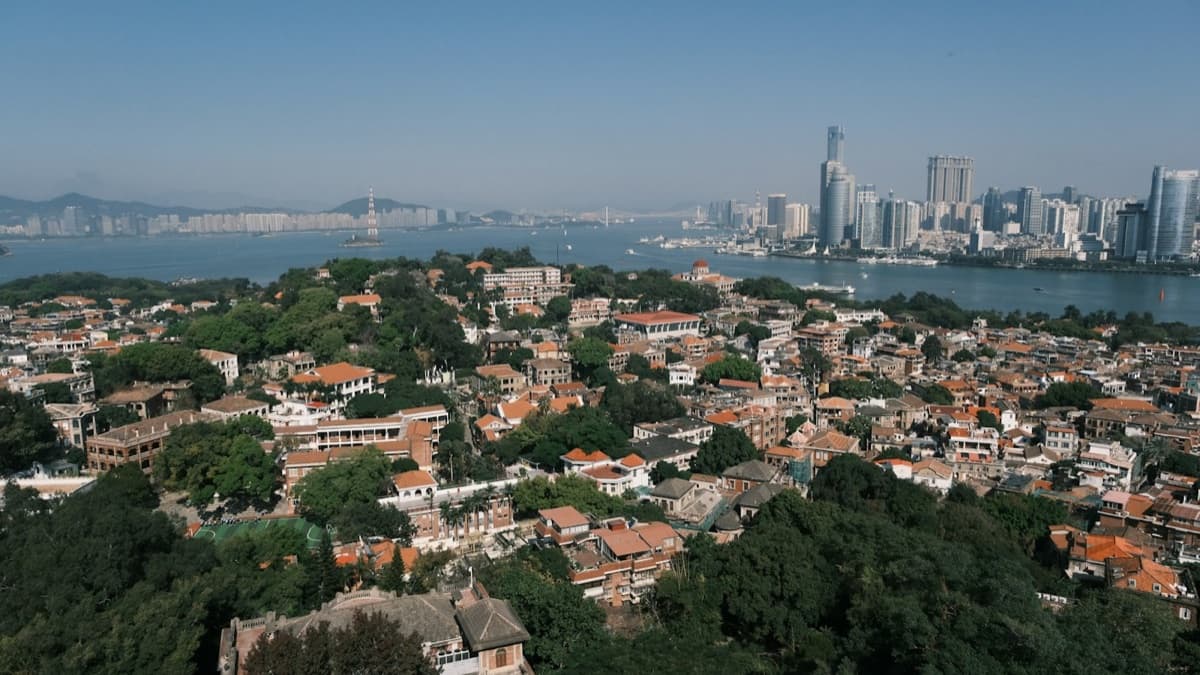 Gulangyu’s red rooftops and trees across the water from Xiamen’s skyline