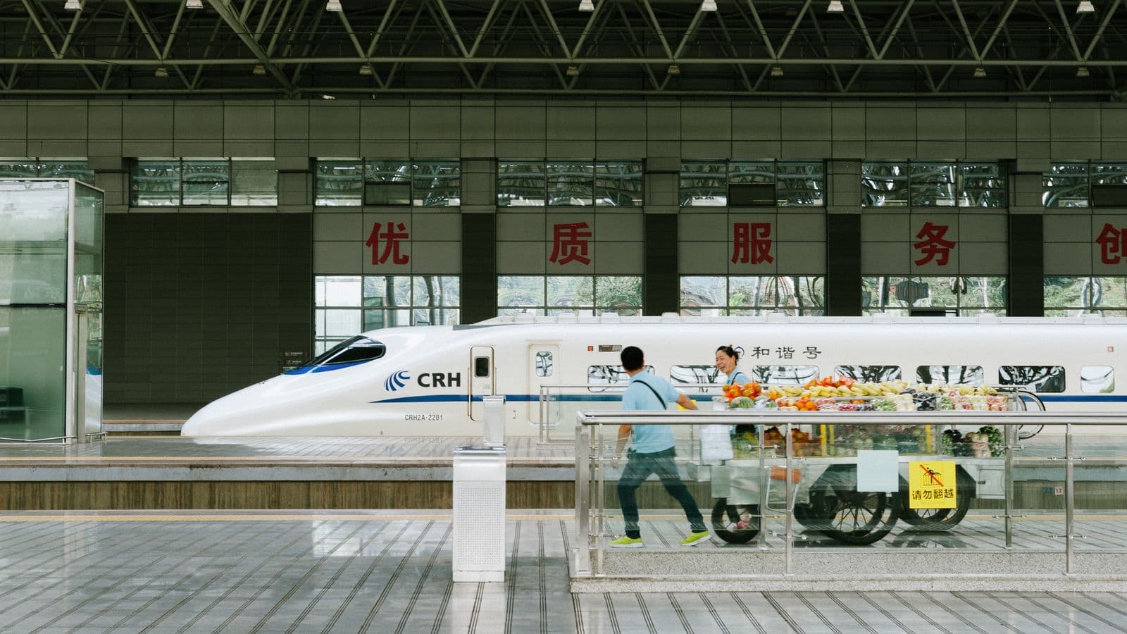 People and a refreshment trolley beside a Chinese high-speed train at Yichang station