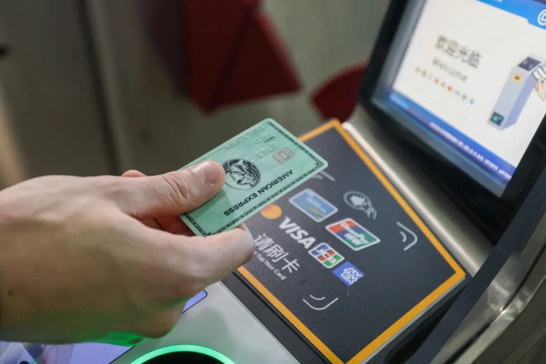 A contactless American Express card held at a marked Beijing Subway fare-gate reader