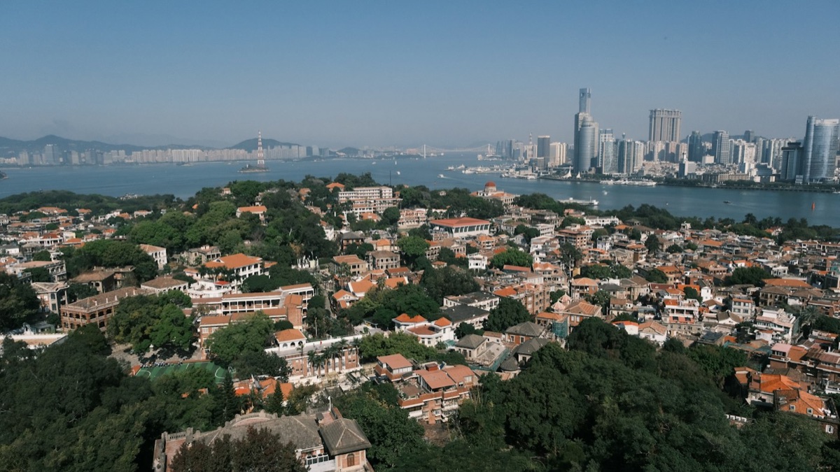 Gulangyu’s red rooftops and trees across the water from Xiamen’s skyline